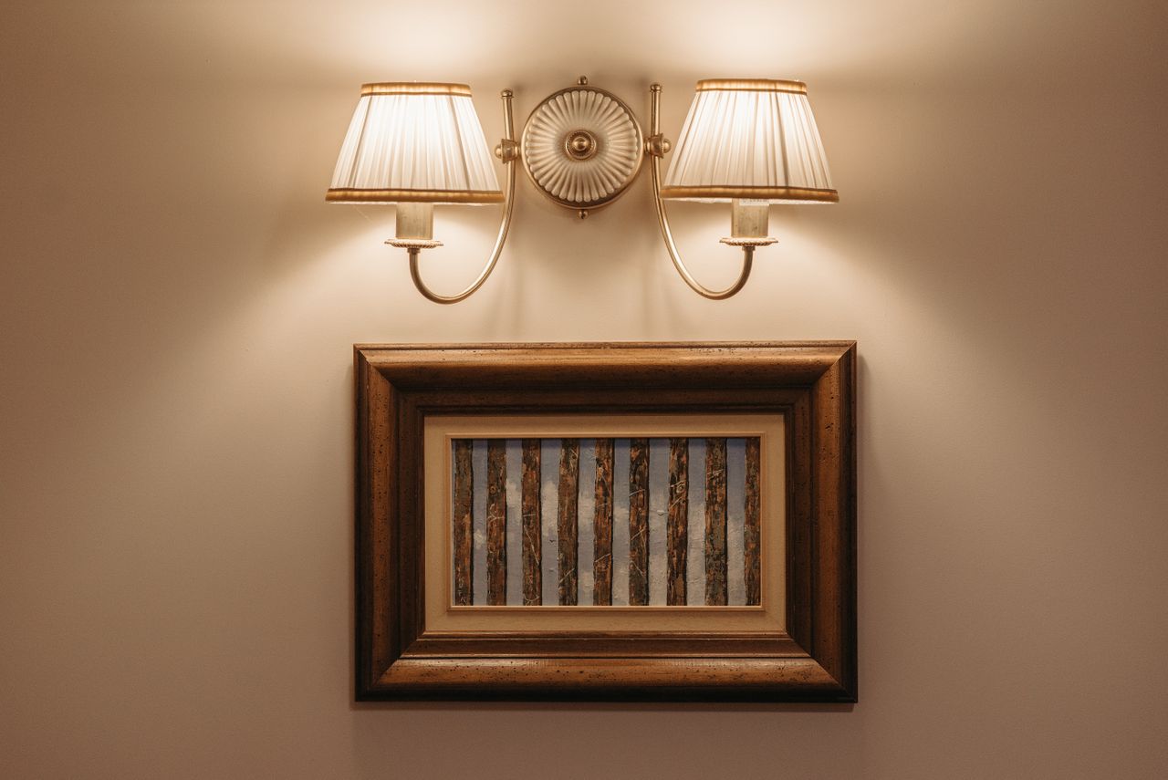 Softly lit wall light illuminating a framed artwork on a white wall.