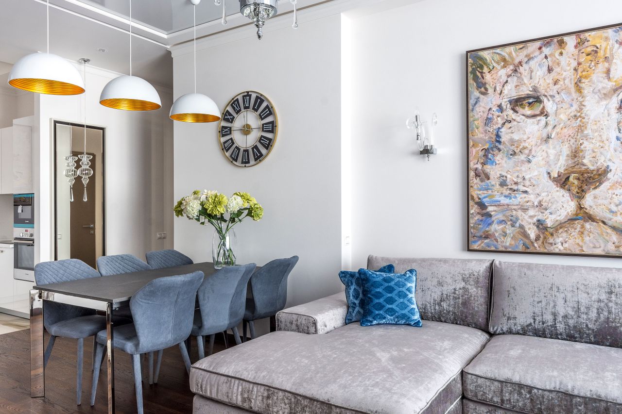 Interior design of cozy living room with comfortable sofa with cushions and table with flowers in vase in studio